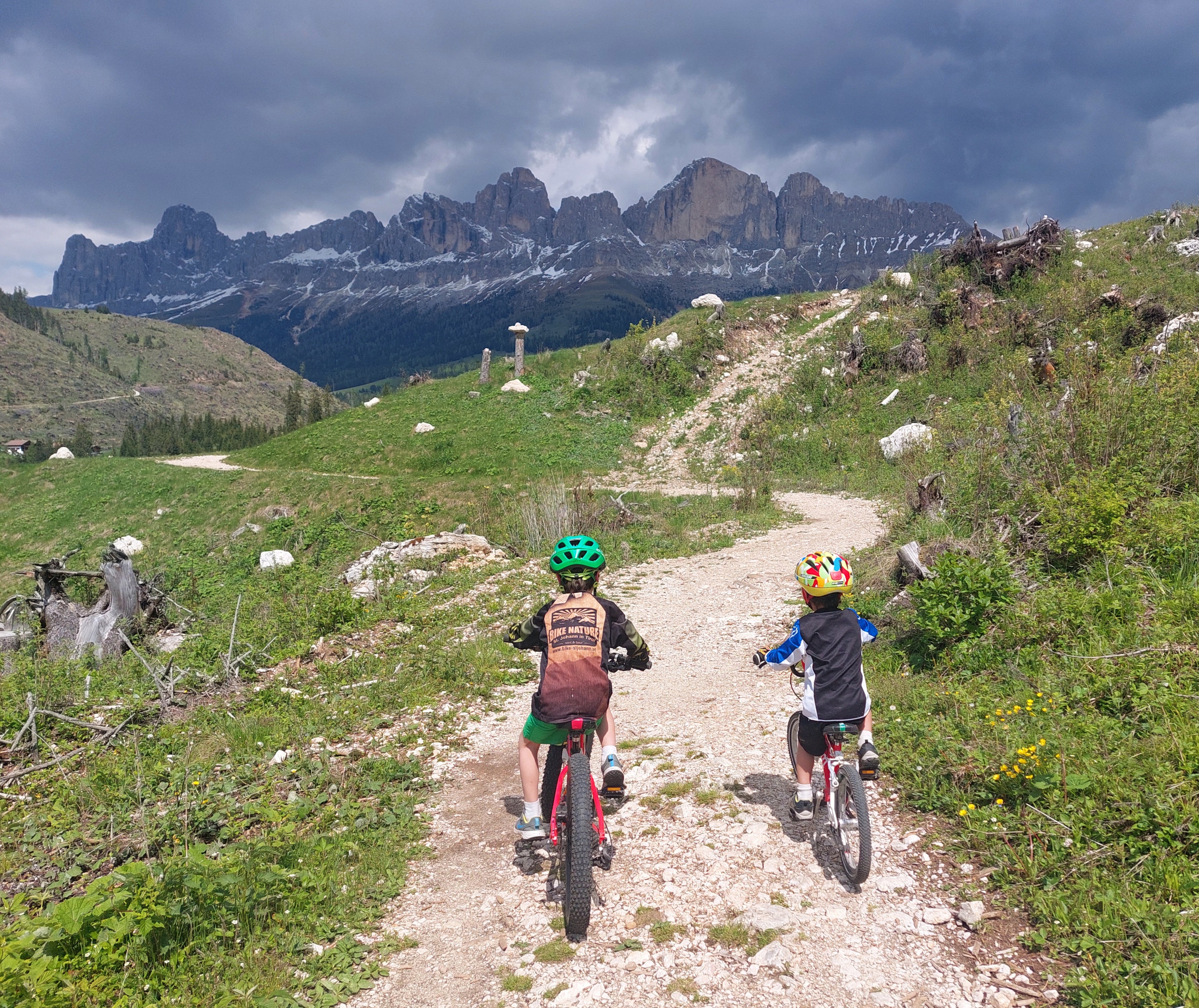 Twee kinderen fietsen op een wandelpad in de Italiaanse Alpen op fietsen van woom.